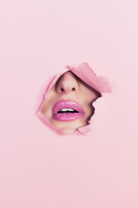 woman's face peeking through the hole in a pink cardboard